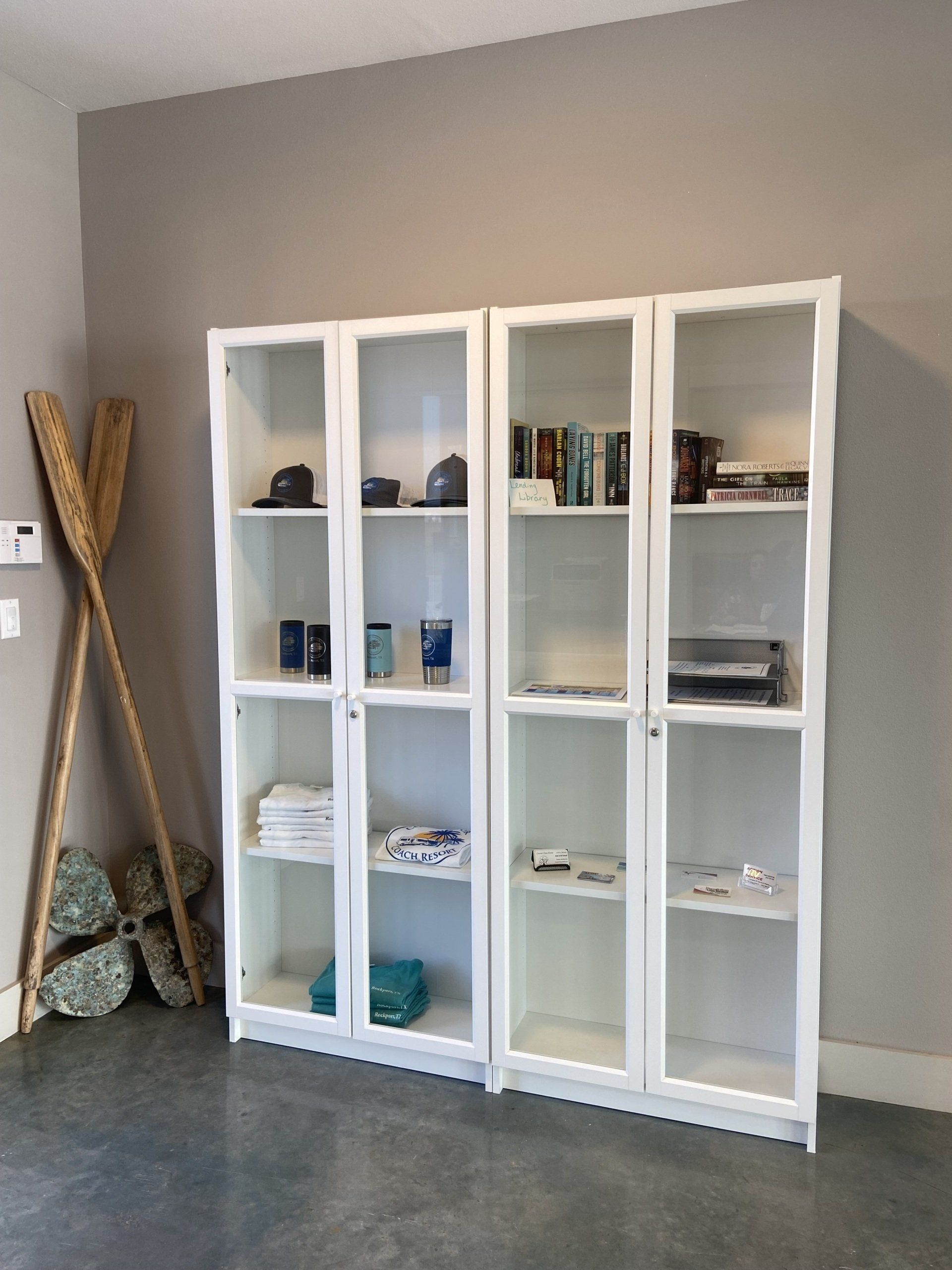 A row of white shelves with glass doors in a room.