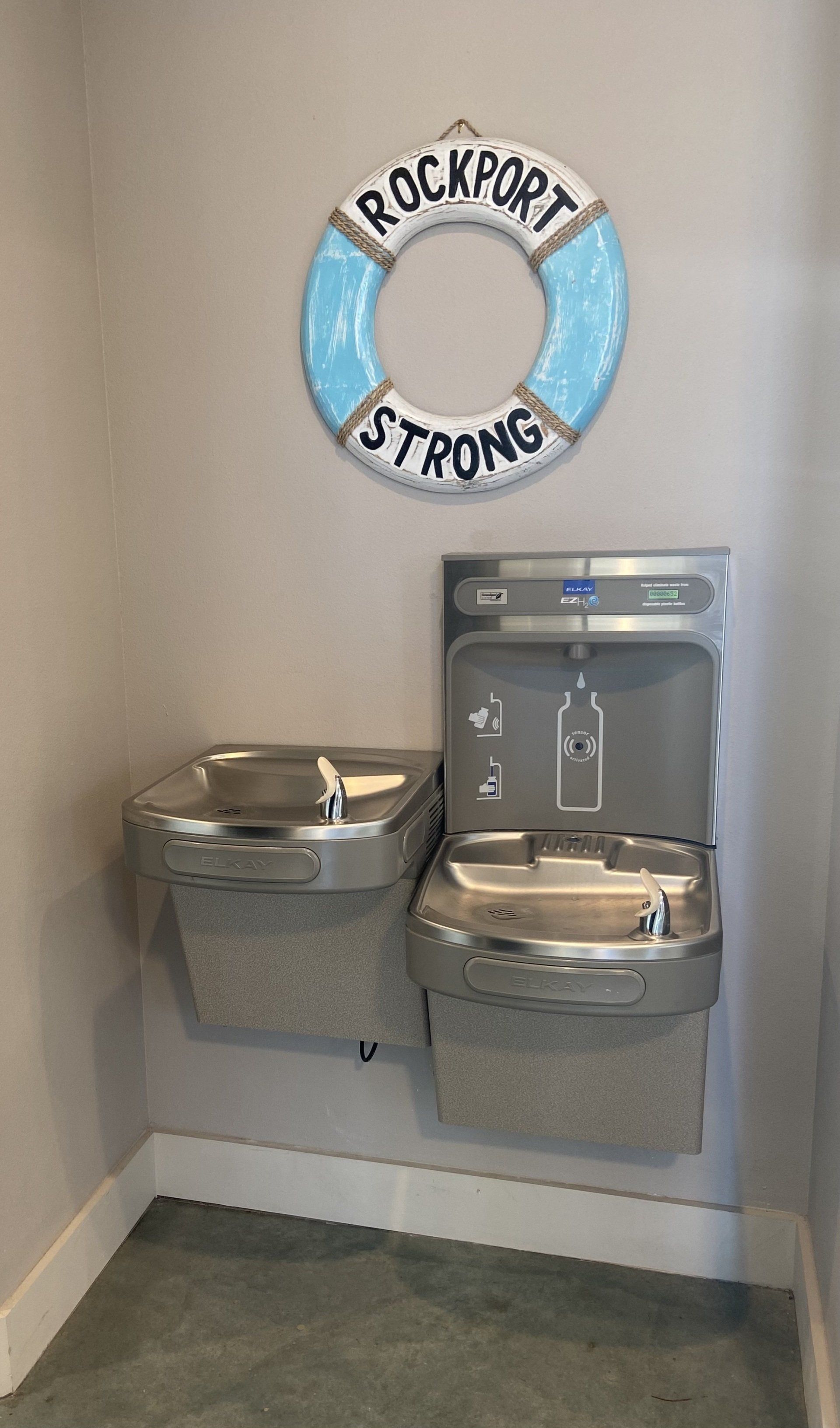 A room with two water fountains and a life preserver on the wall.