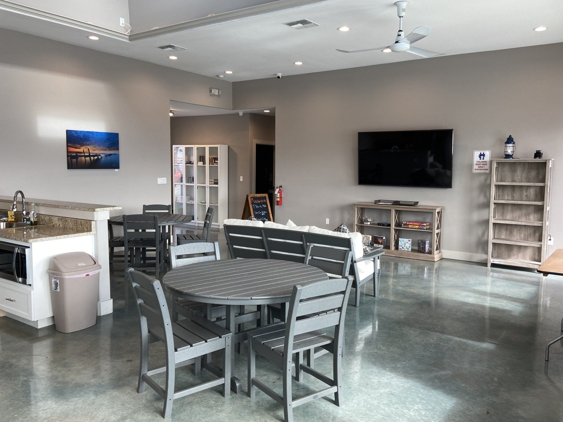 A large room with tables and chairs and a flat screen tv.
