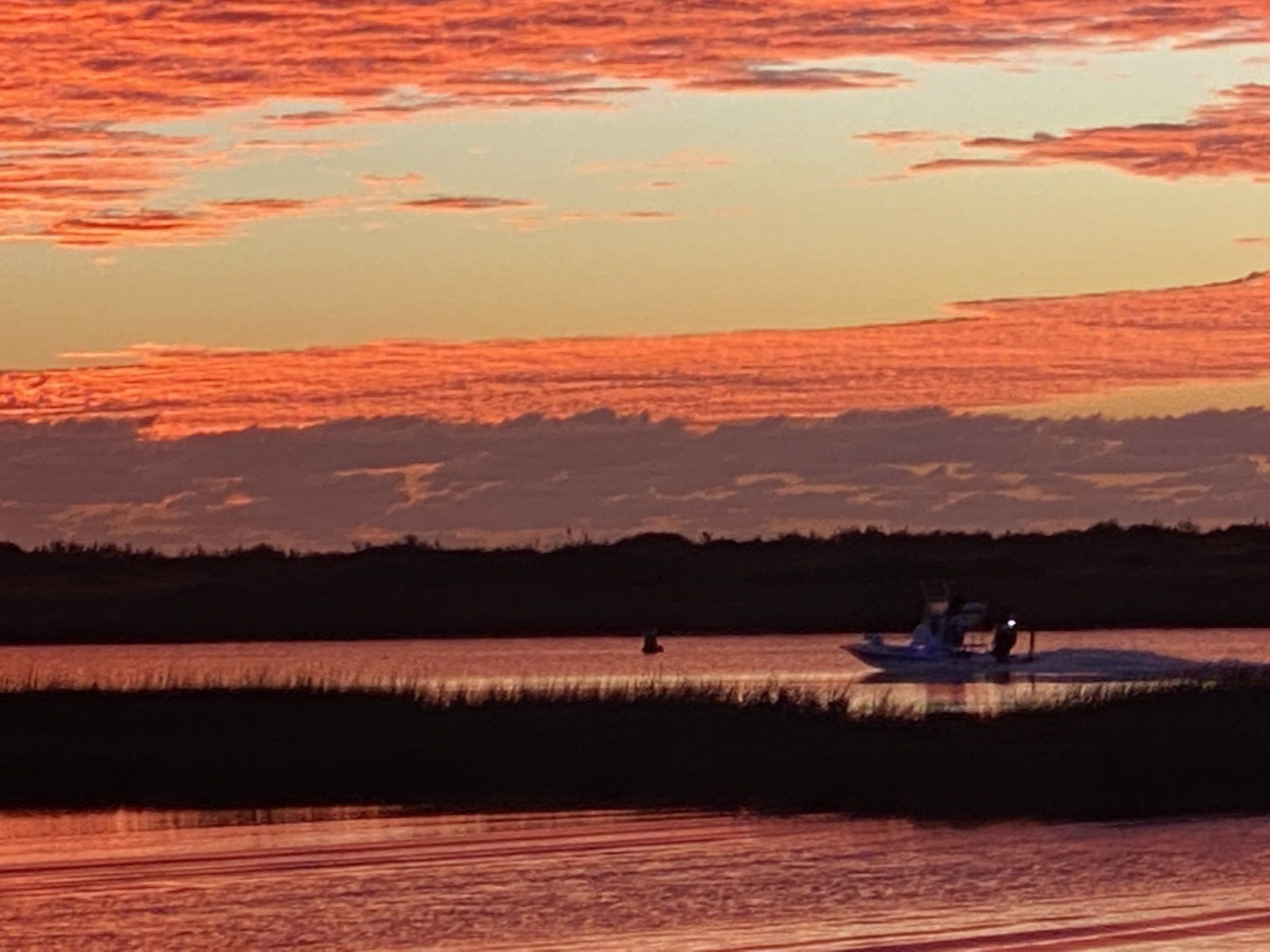 A boat is floating on a body of water at sunset.