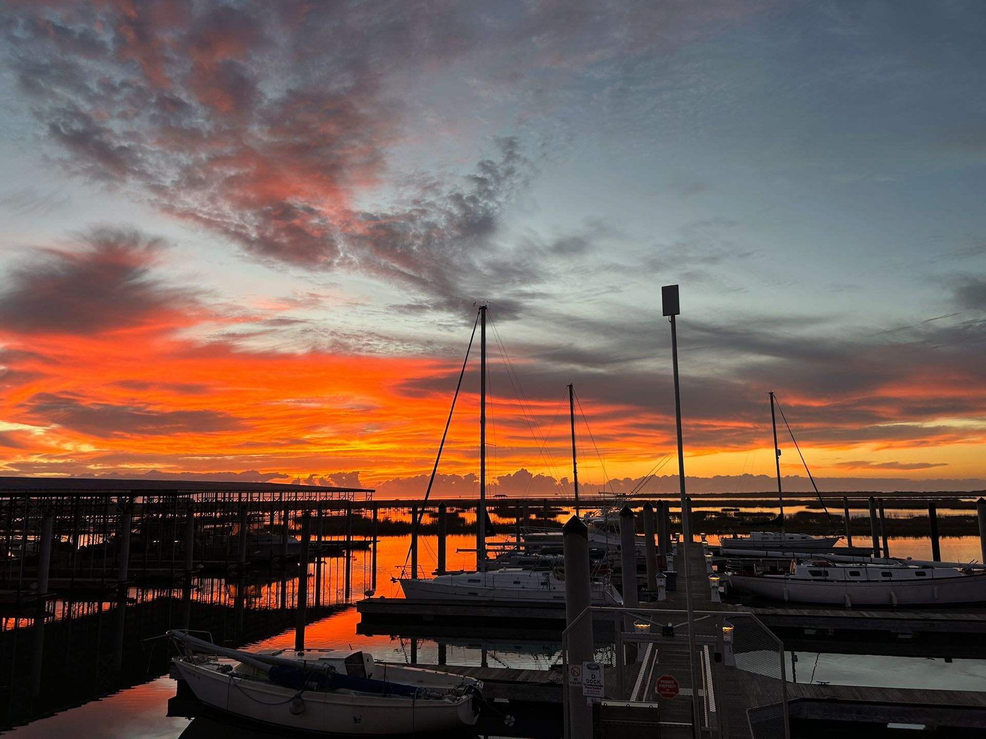 A sunset over a marina with boats docked in the water.