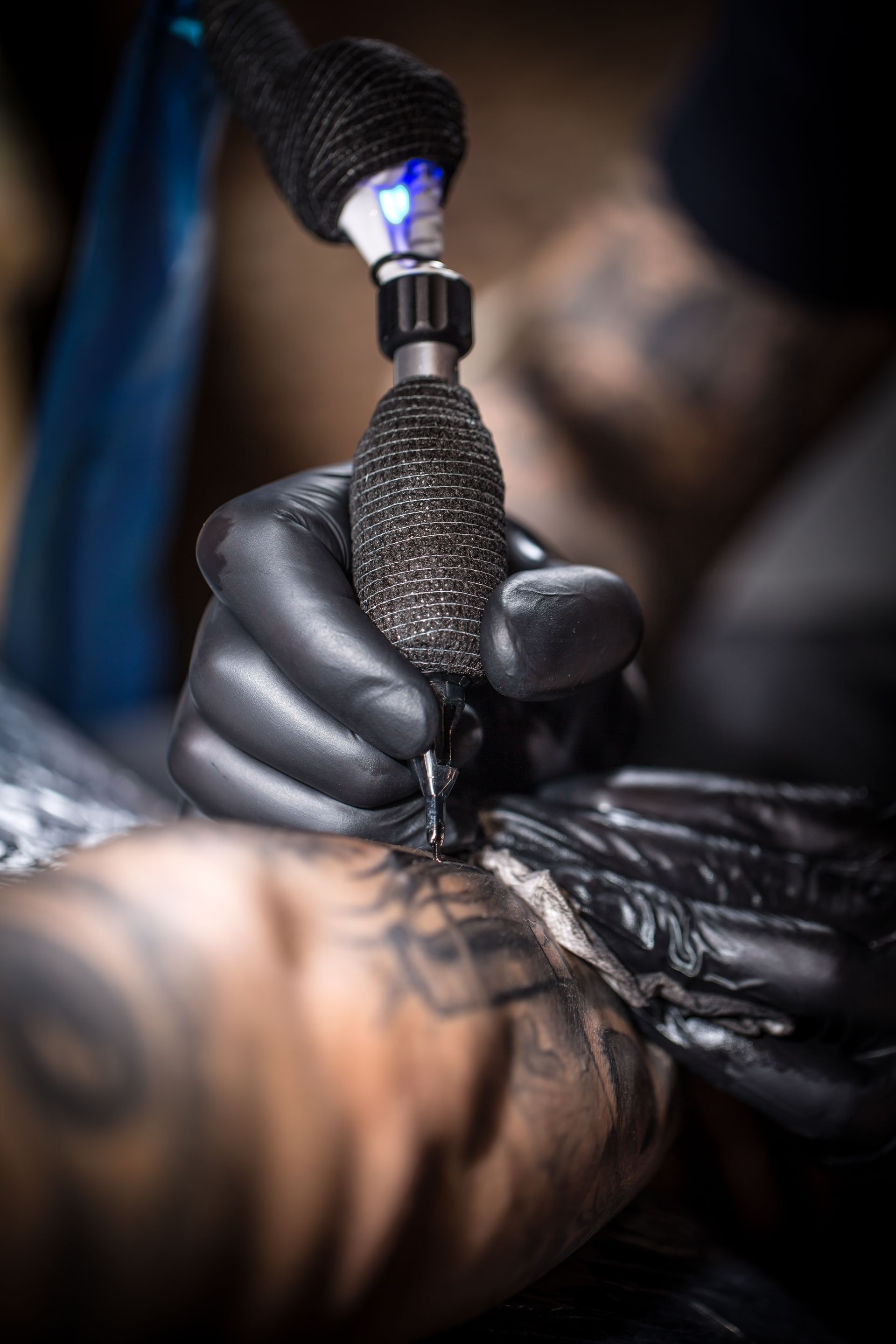 Gloved tattoo artist using a tattoo machine on skin in a close-up shot
