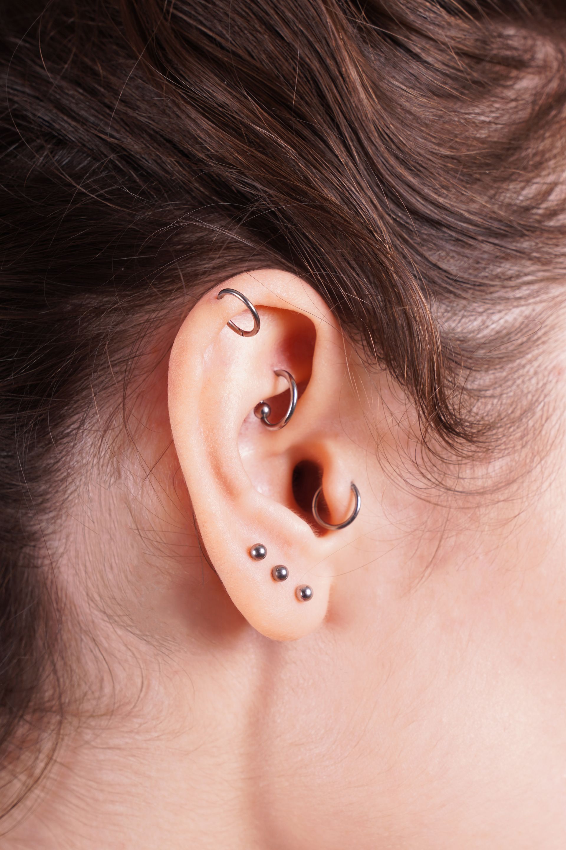 Close-up of an ear with multiple piercings and small silver earrings