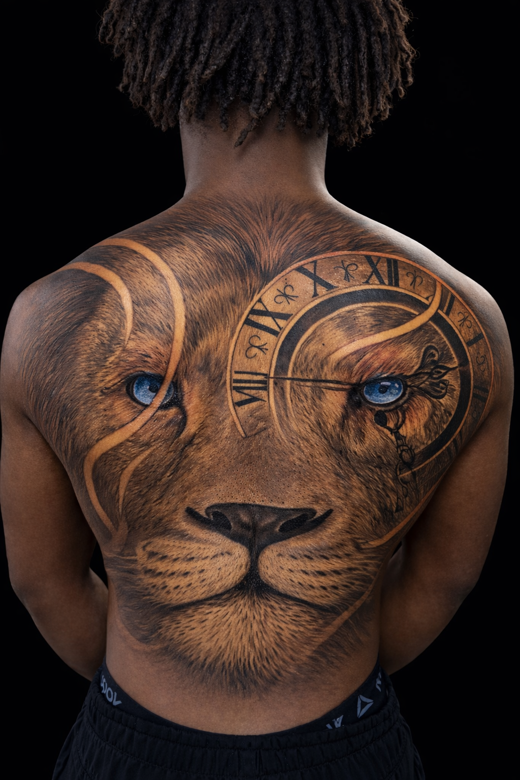Person showing a lion tattoo covering the back, with blue eyes and Roman numerals on the forehead