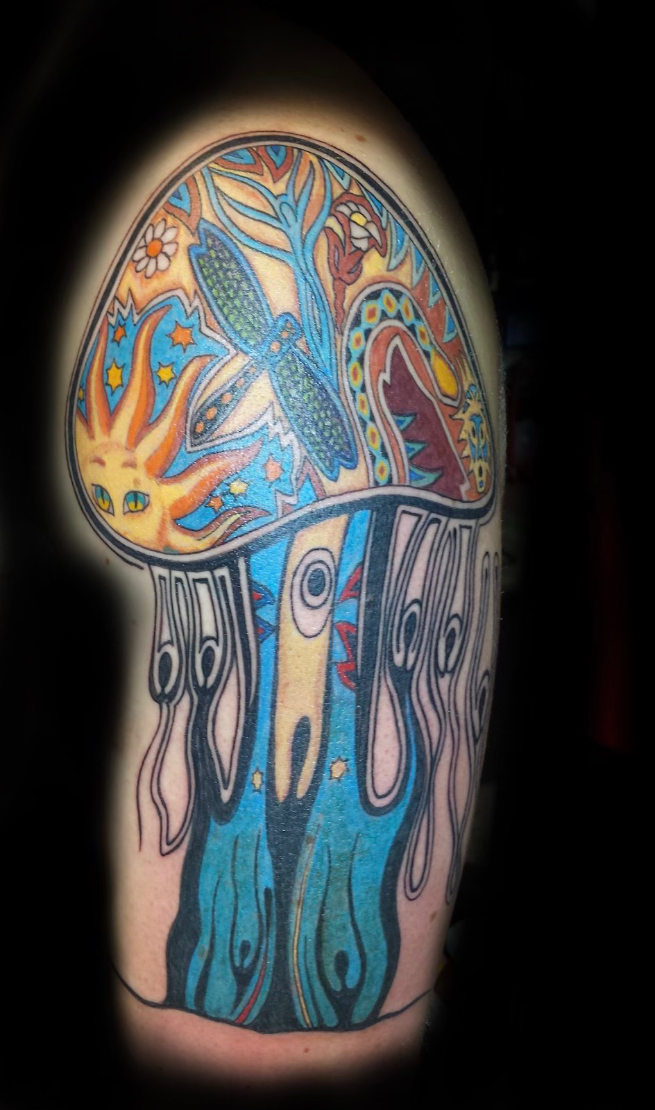Gloved hands tattooing a person’s shoulder with a tattoo machine