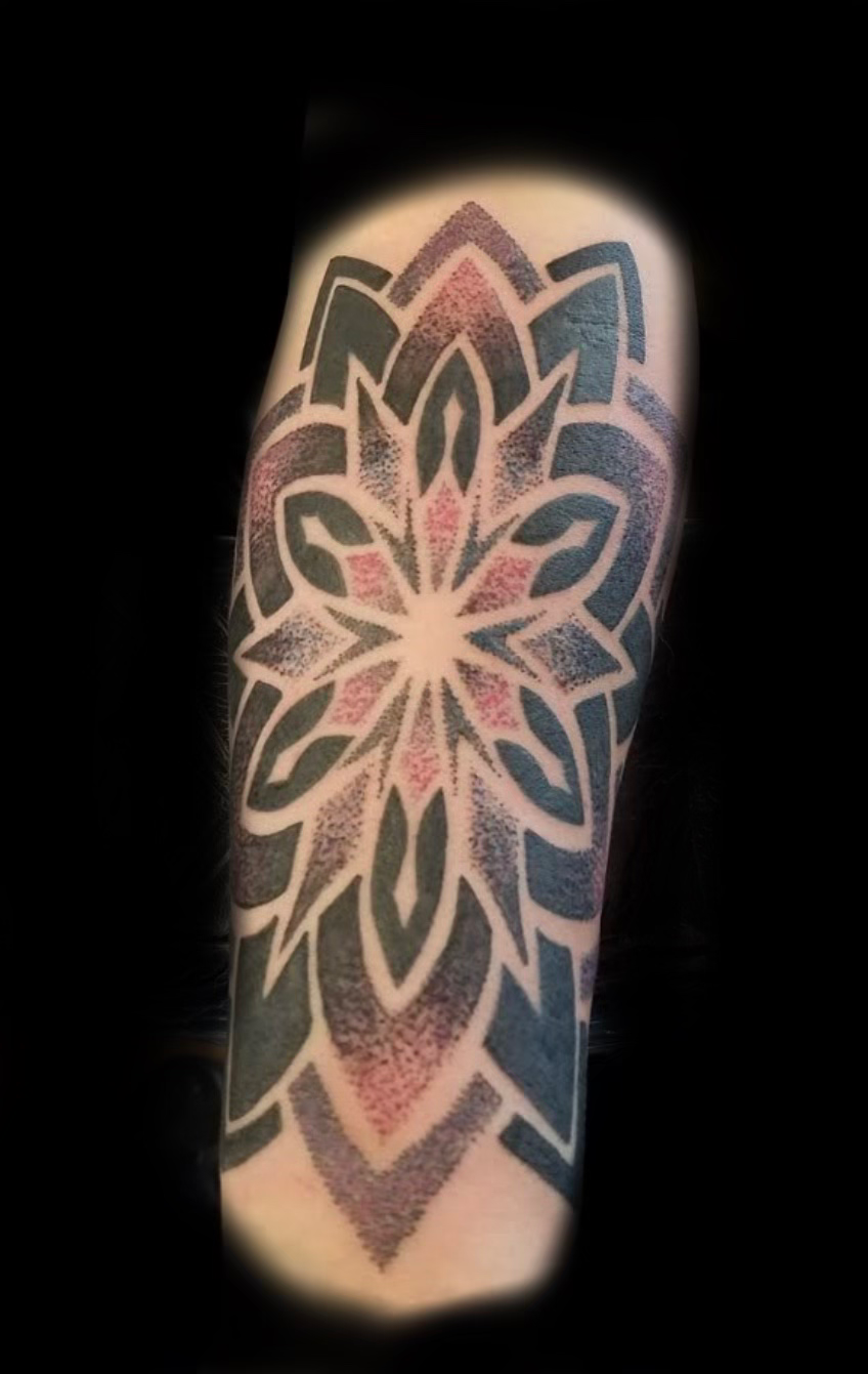 Tattooed forearms crossed over a bare chest in dramatic low light