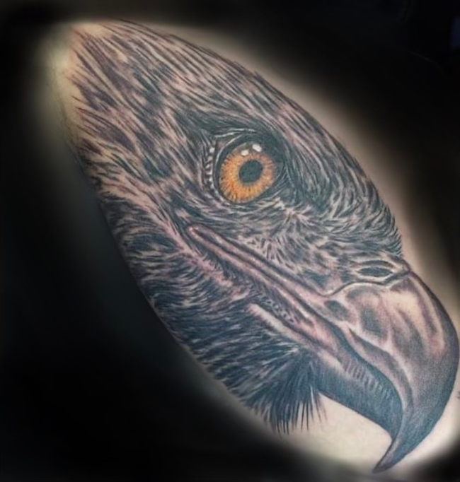 Tattoo artist outlining a floral design on skin with a black-gloved hand and tattoo machine