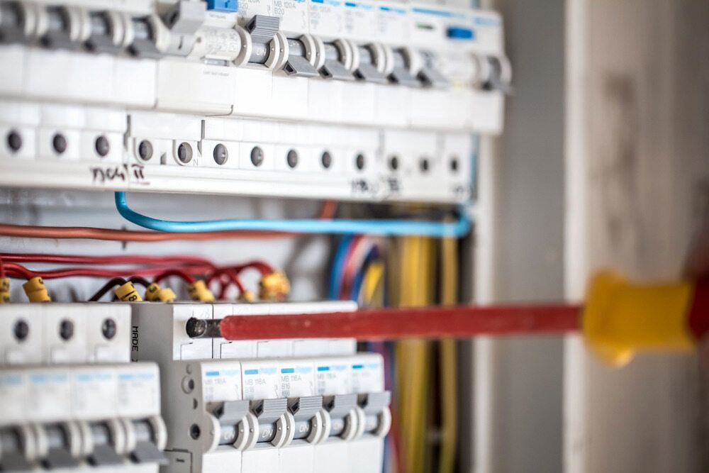 A Circuit Breaker Panel; a Hand Using a Screwdriver on a Breaker — Darwin Electrical Services in Rural & Remote, NT