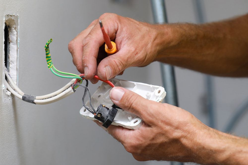 Electrician Wiring an Electrical Outlet, Using a Screwdriver, Indoors — Darwin Electrical Services in Humpty Doo, NT
