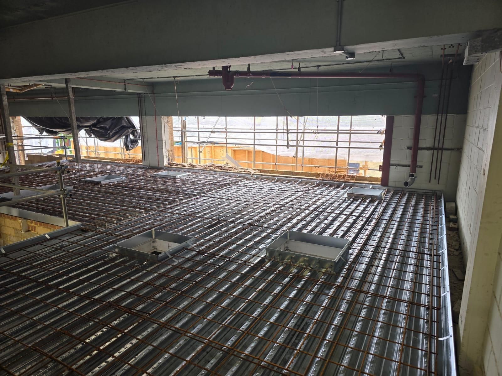 Construction site with metal rebar flooring and concrete columns inside an unfinished building