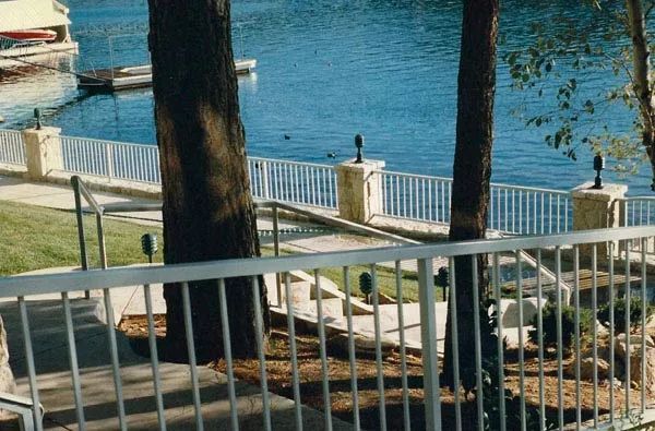 A view of a lake through a fence with trees in the foreground