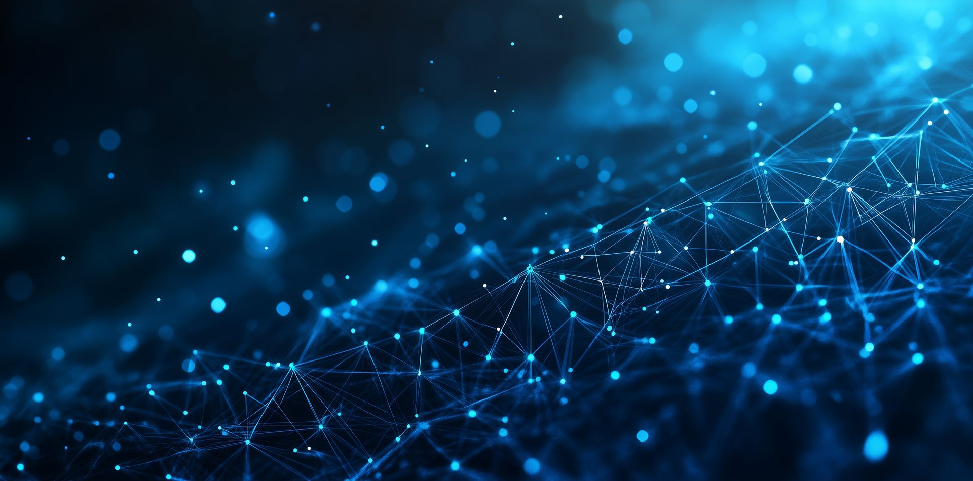 Woman with glasses focused on a computer screen, working in a dim office with a colleague.