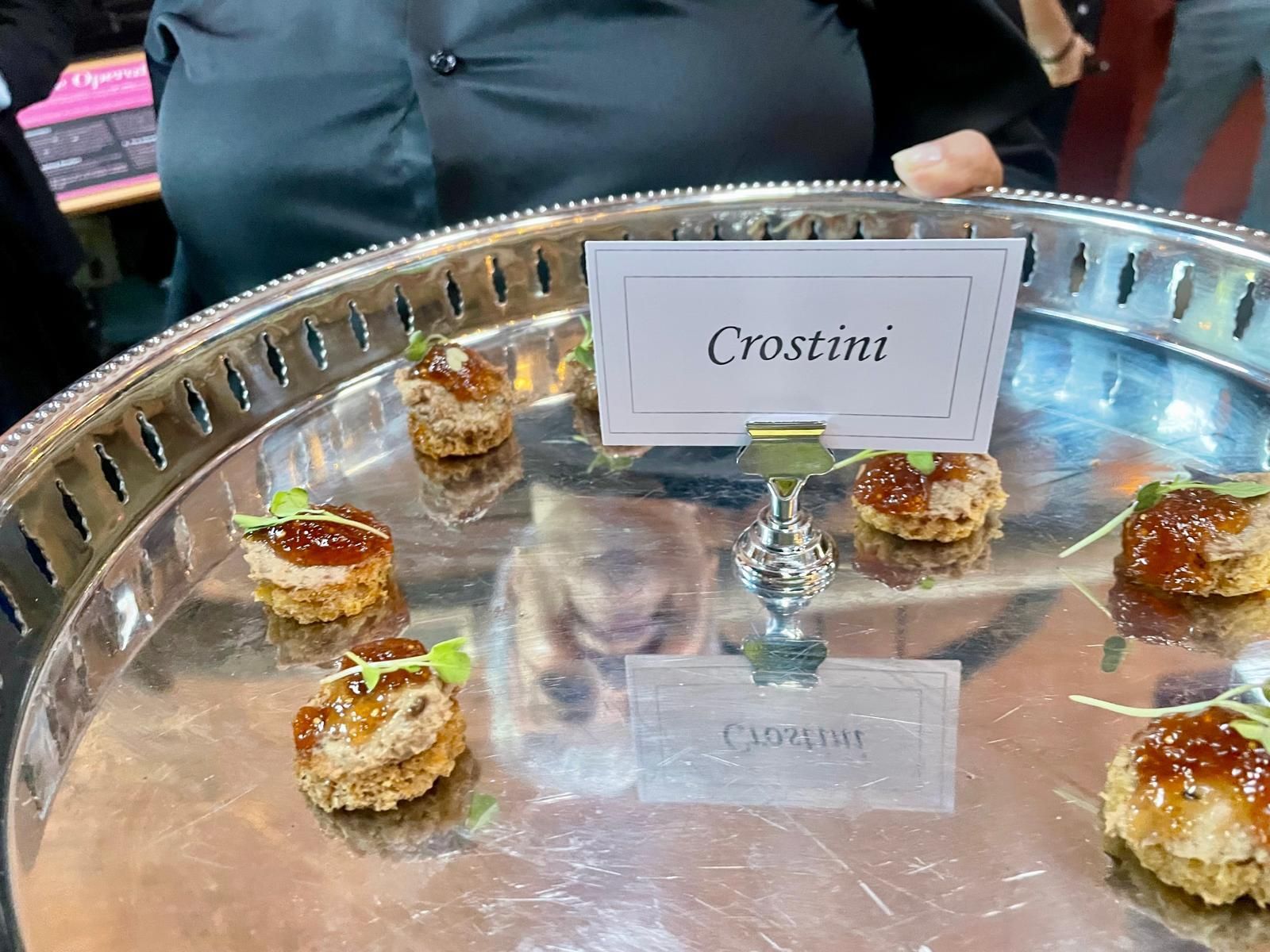 Silver tray of crostini appetizers with labels.