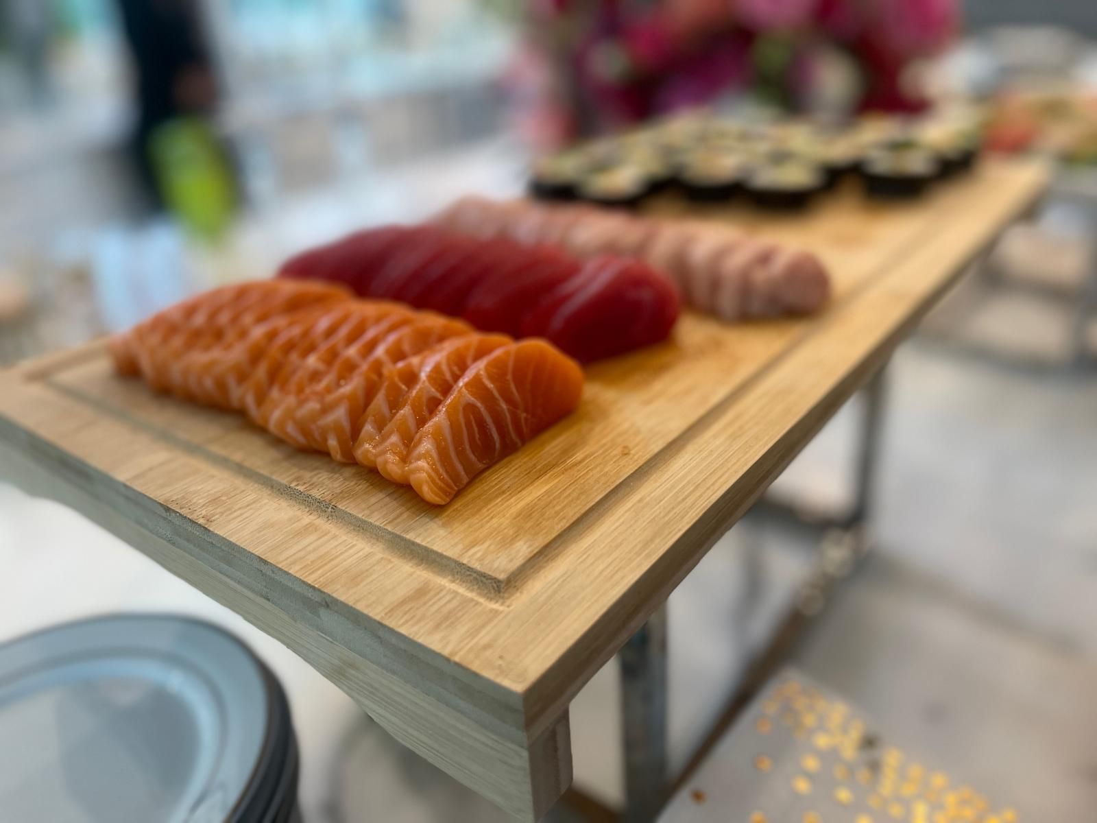 Sushi platter on a wooden board: salmon, tuna, and other fish.