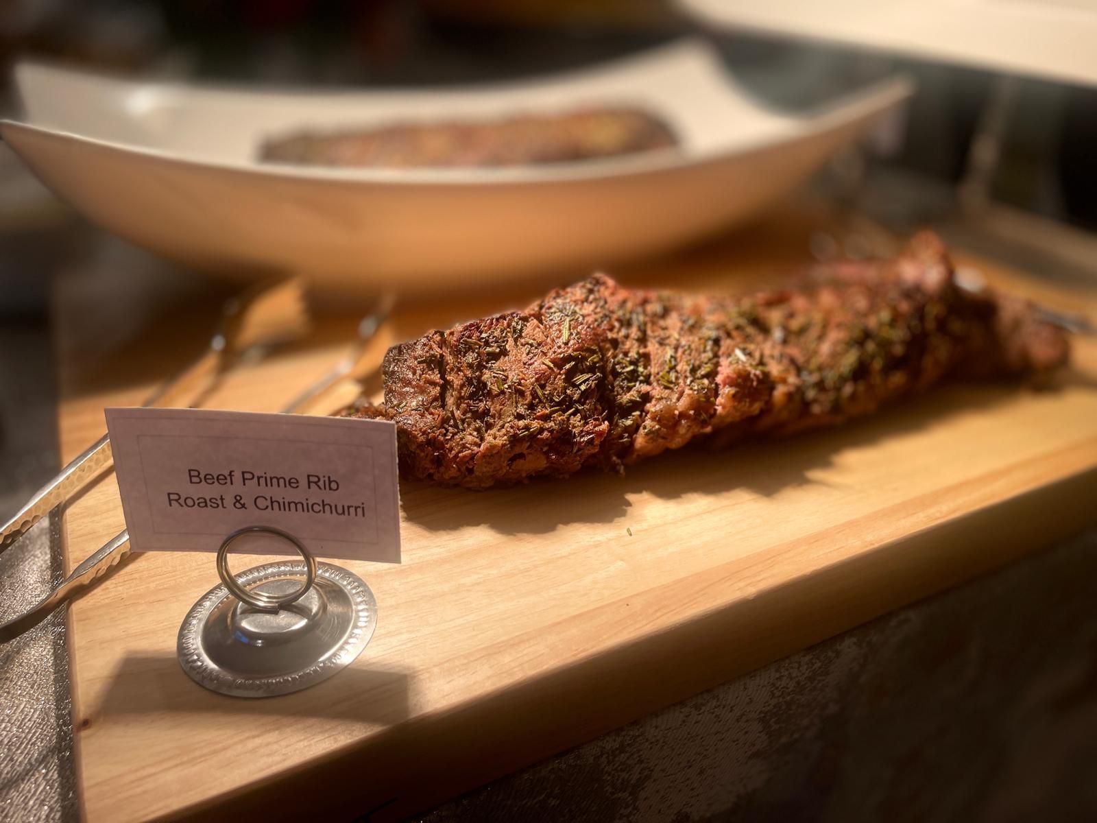 Roasted meat rib on a wooden board with a sign that reads