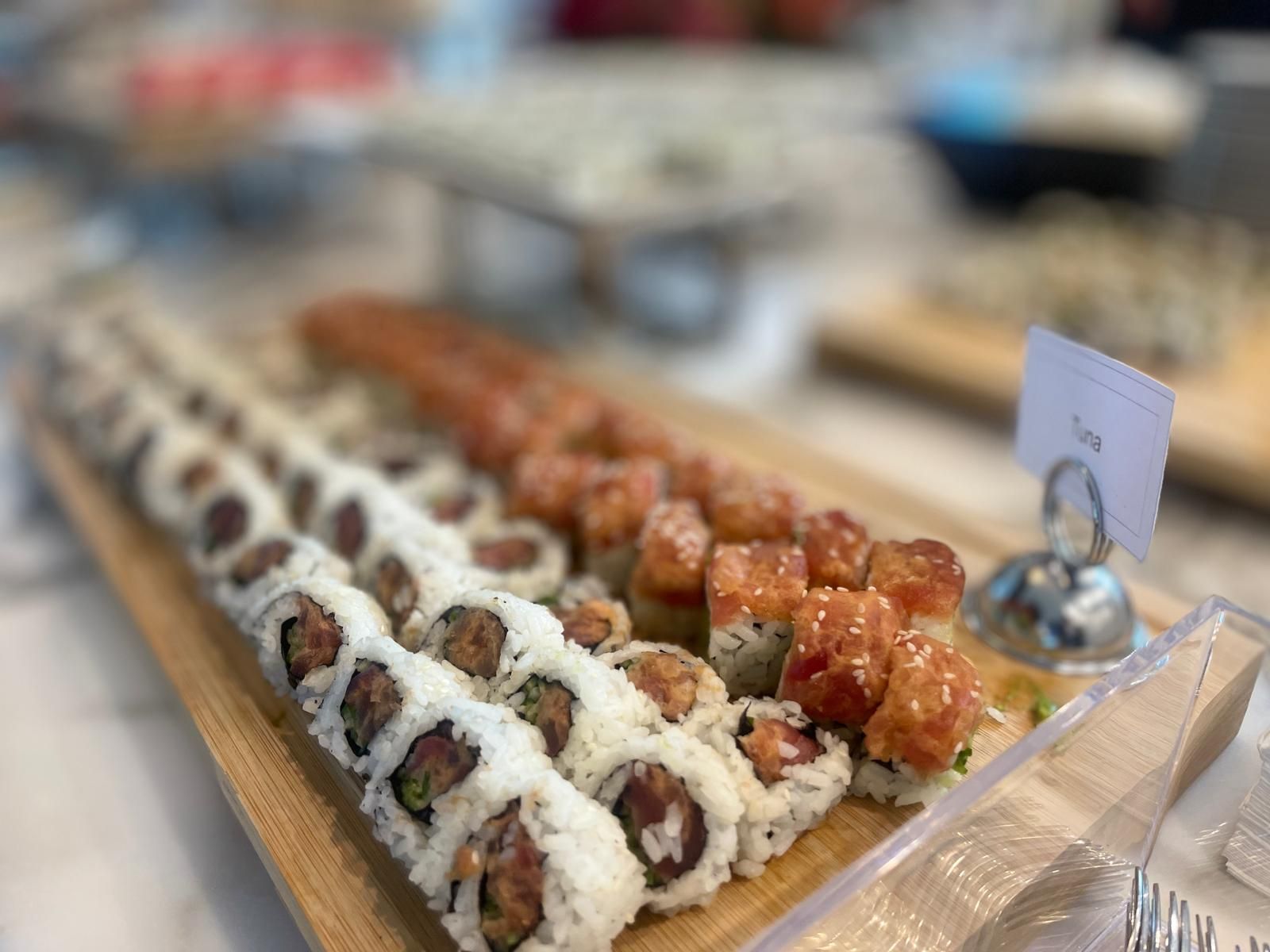 Sushi rolls arranged on a wooden platter, ready to be served at an event.