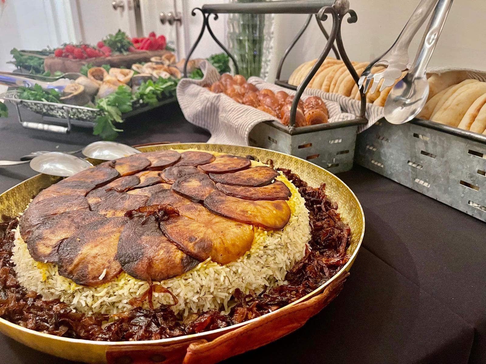 A buffet with Persian dishes: saffron rice with fried potatoes, bread, and other appetizers.