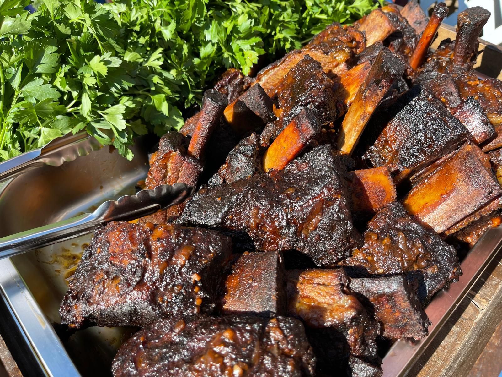 Smoked beef ribs in a metal tray, garnished with parsley.