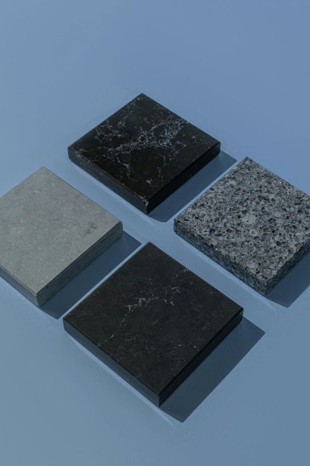 Four different types of granite tiles are stacked on top of each other on a blue surface.