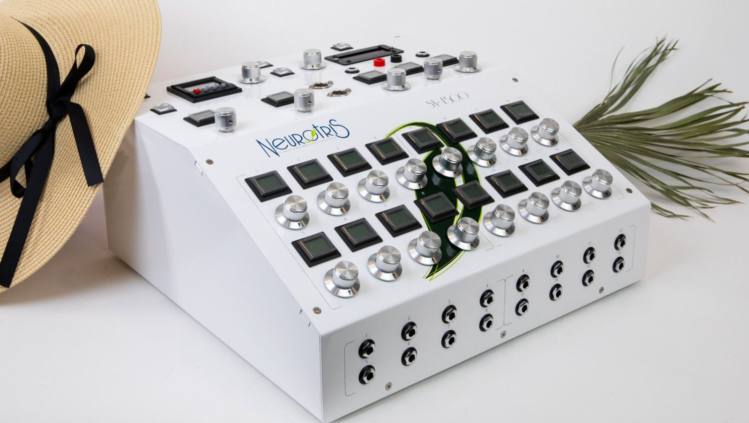 A white box with buttons on it is sitting next to a straw hat.