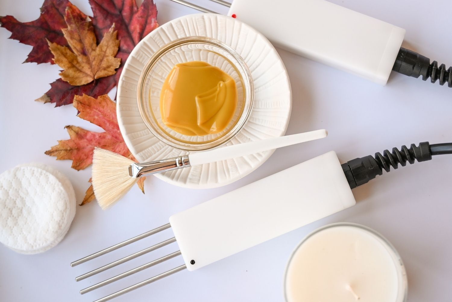 A white plate topped with honey and a brush on a table.