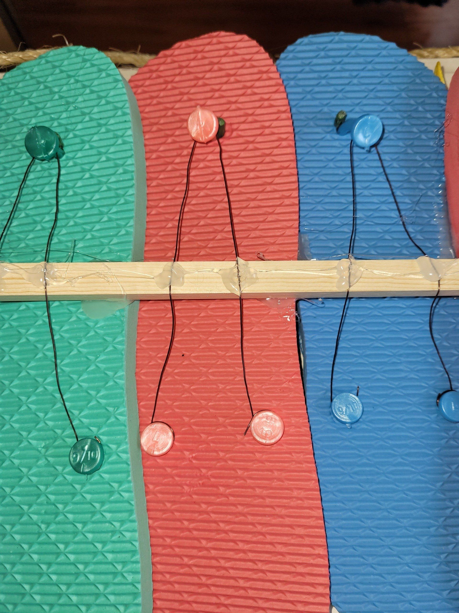 Three pairs of flip flops with buttons attached to them