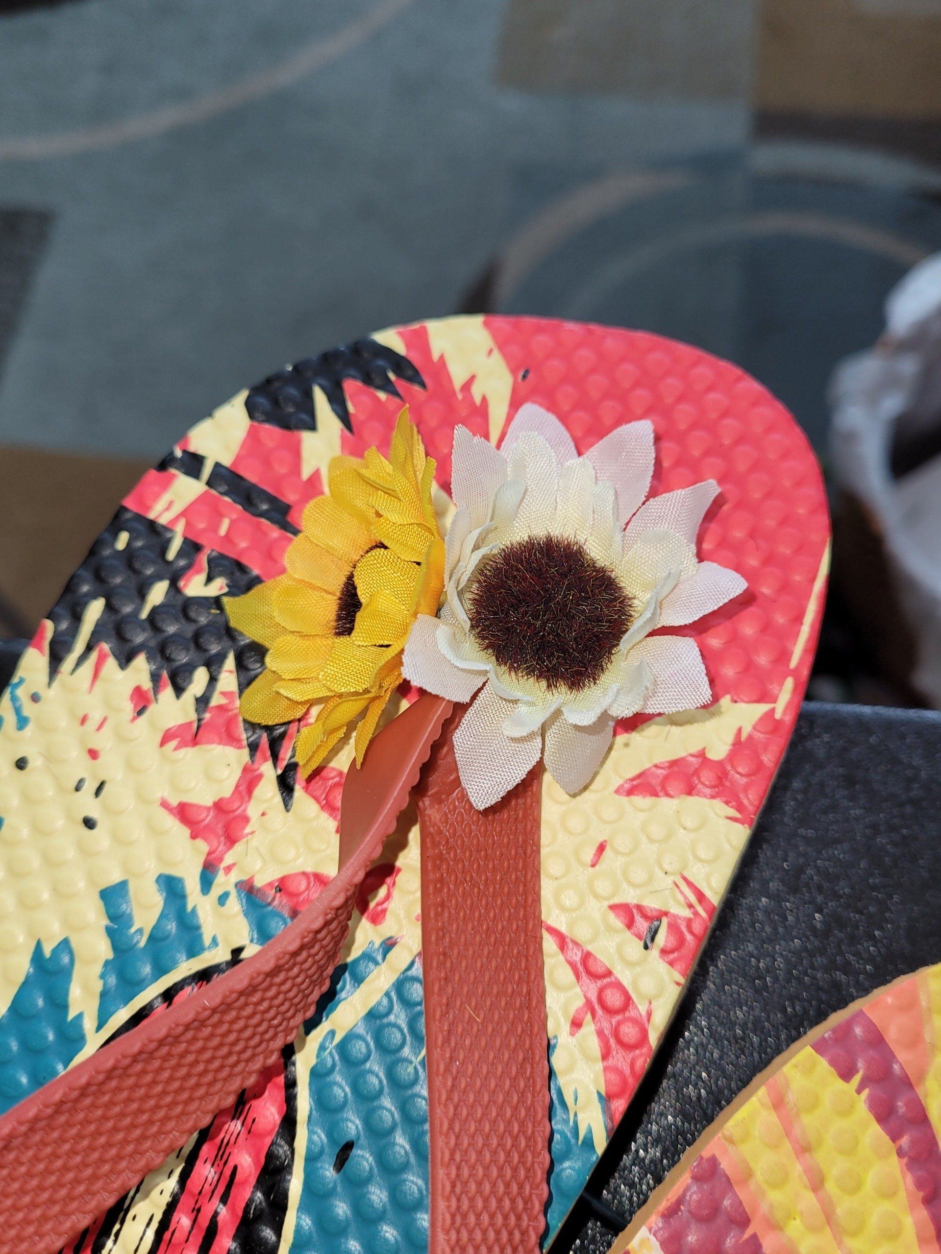 A pair of flip flops with a flower on the bottom