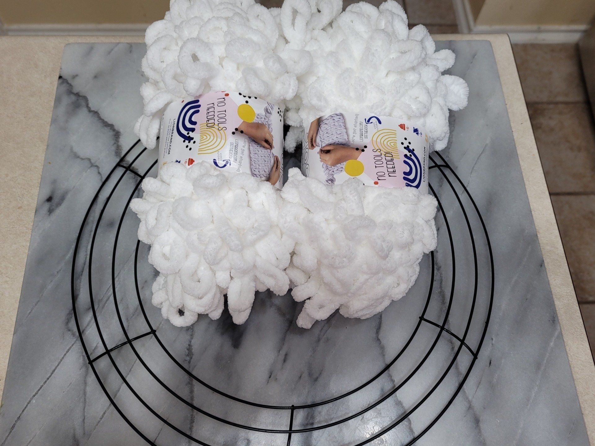 A wreath made of yarn is sitting on top of a wire wreath frame.