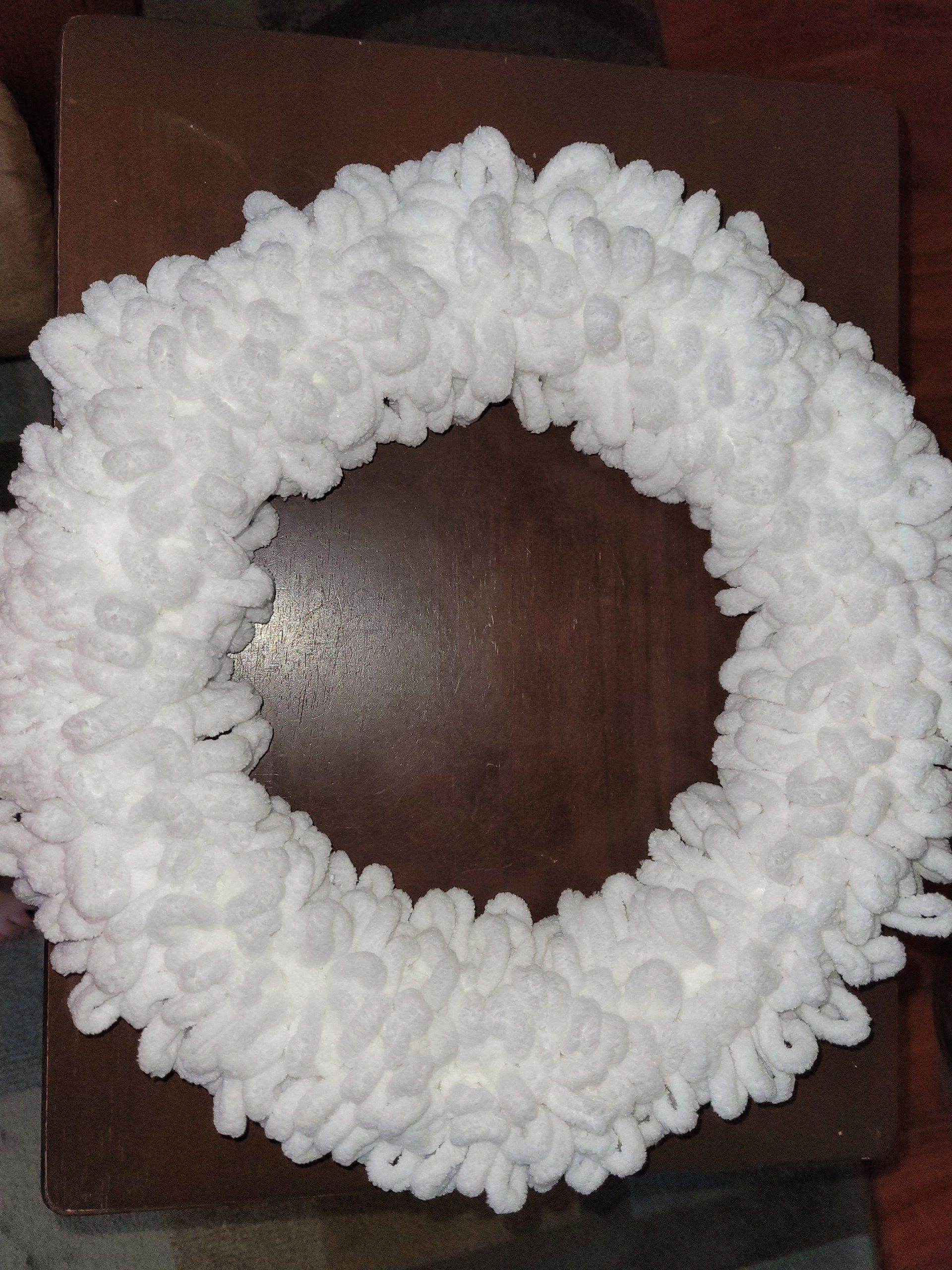 A white wreath is sitting on a wooden table