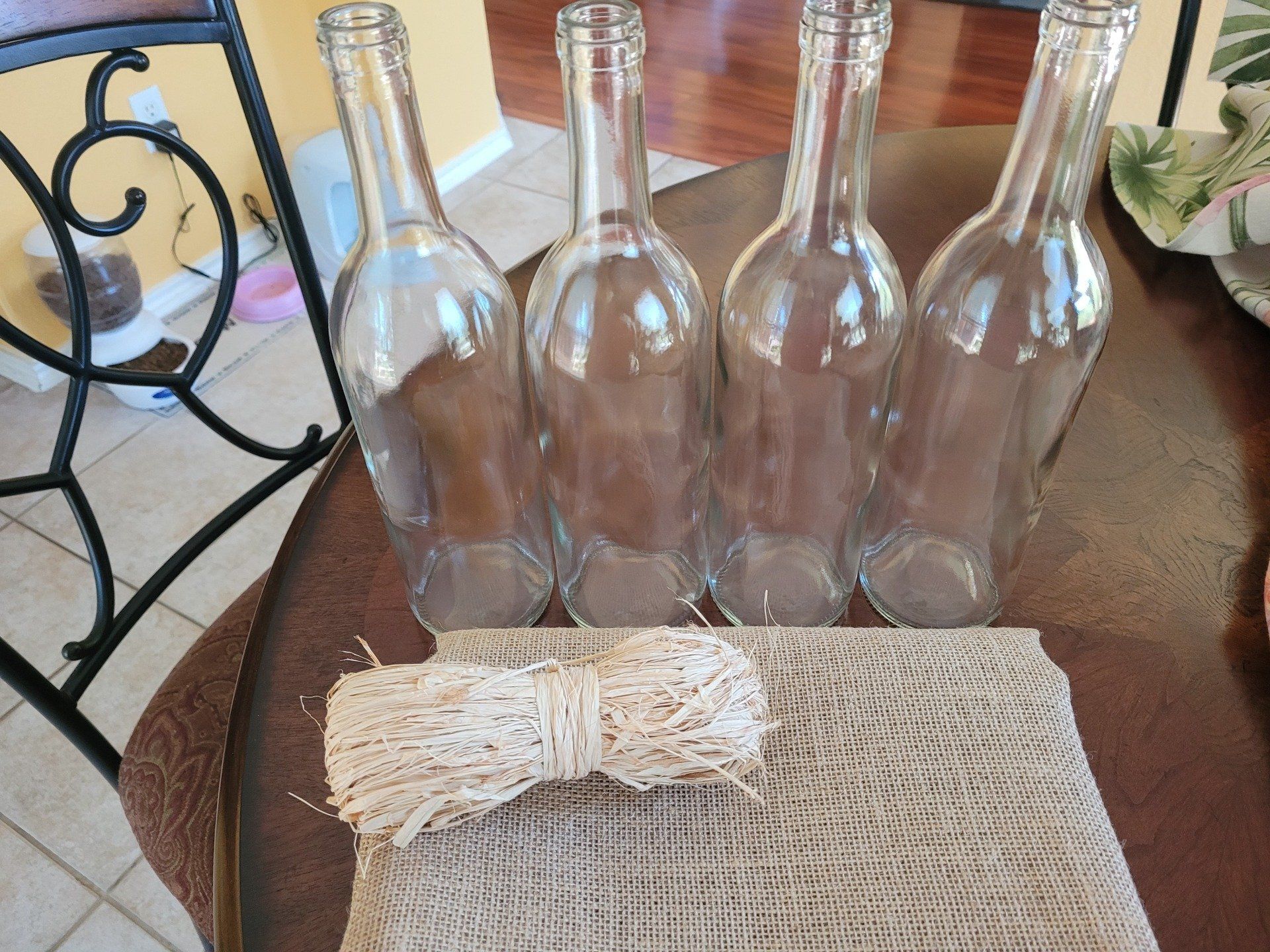 Four empty wine bottles are sitting on a table next to a rope