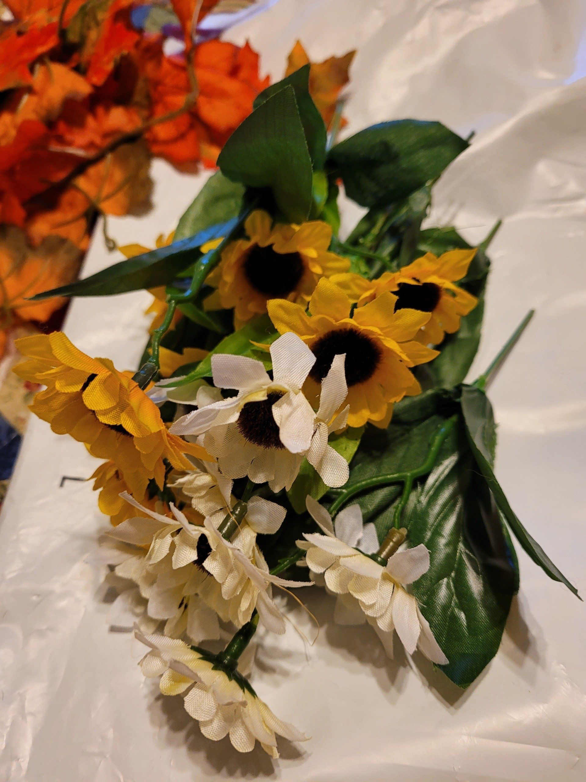 A bunch of sunflowers and daisies are sitting on a table.