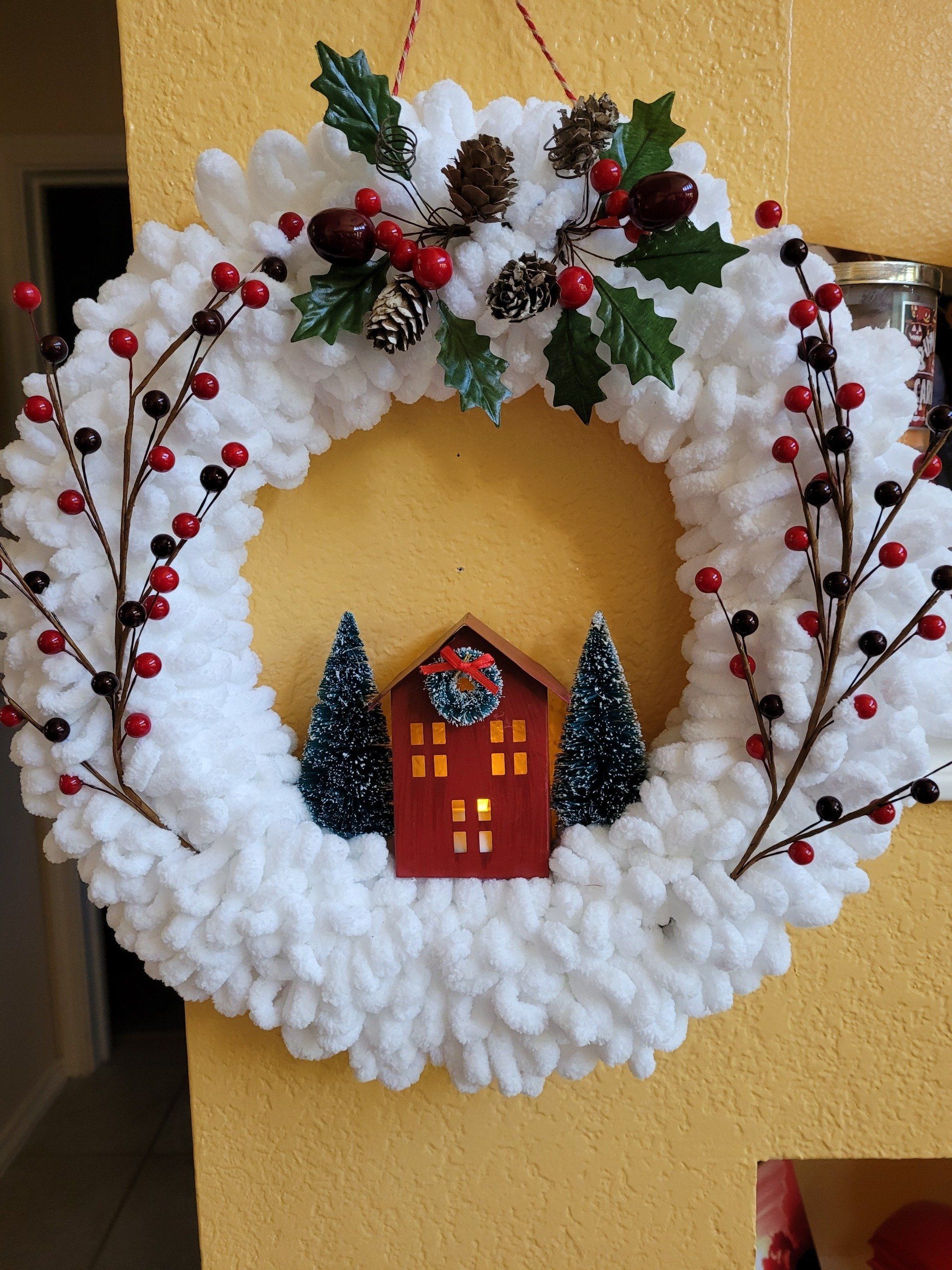 A christmas wreath with a house and trees on it