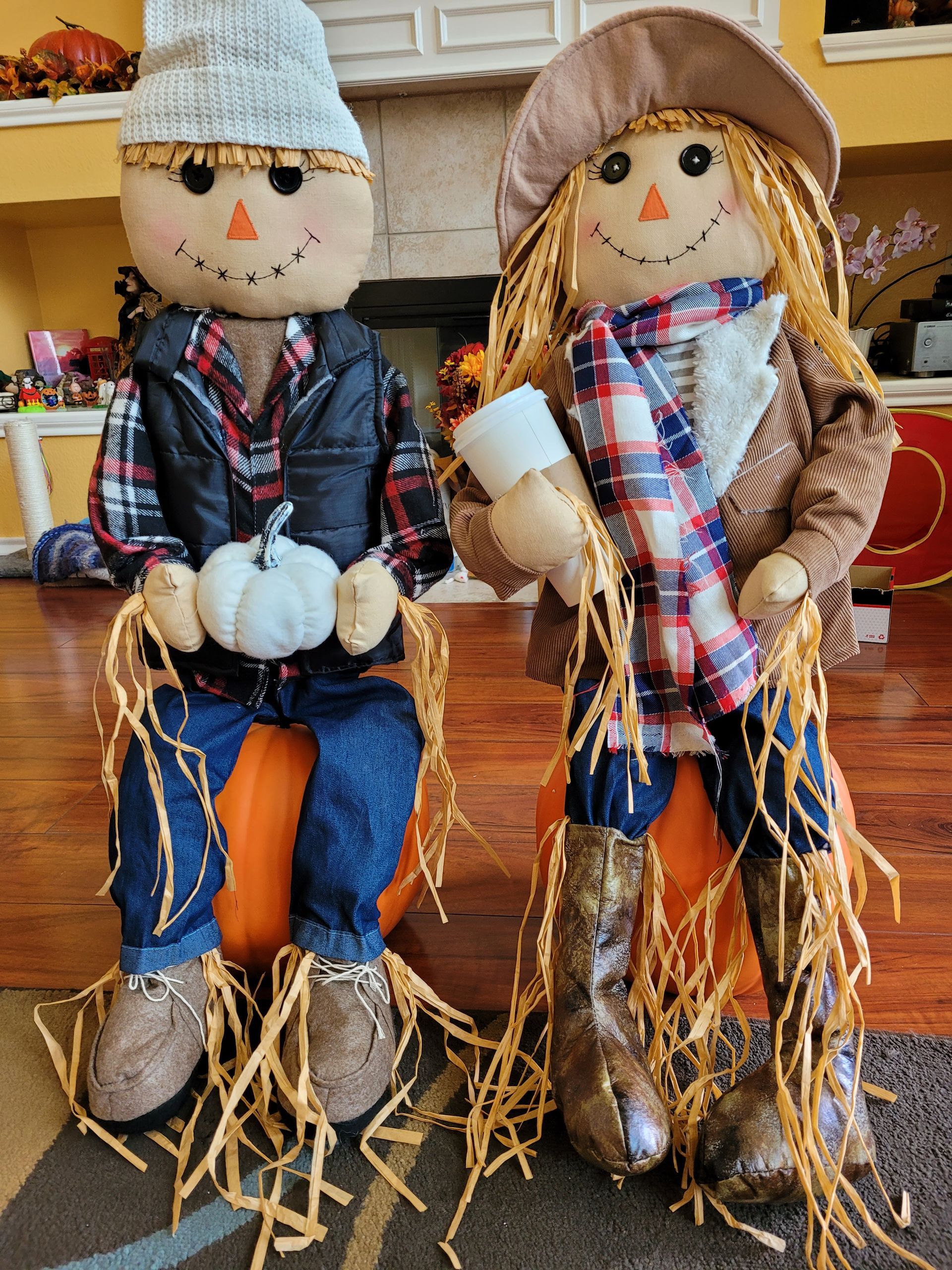 A boy and a girl scarecrow are sitting on pumpkins
