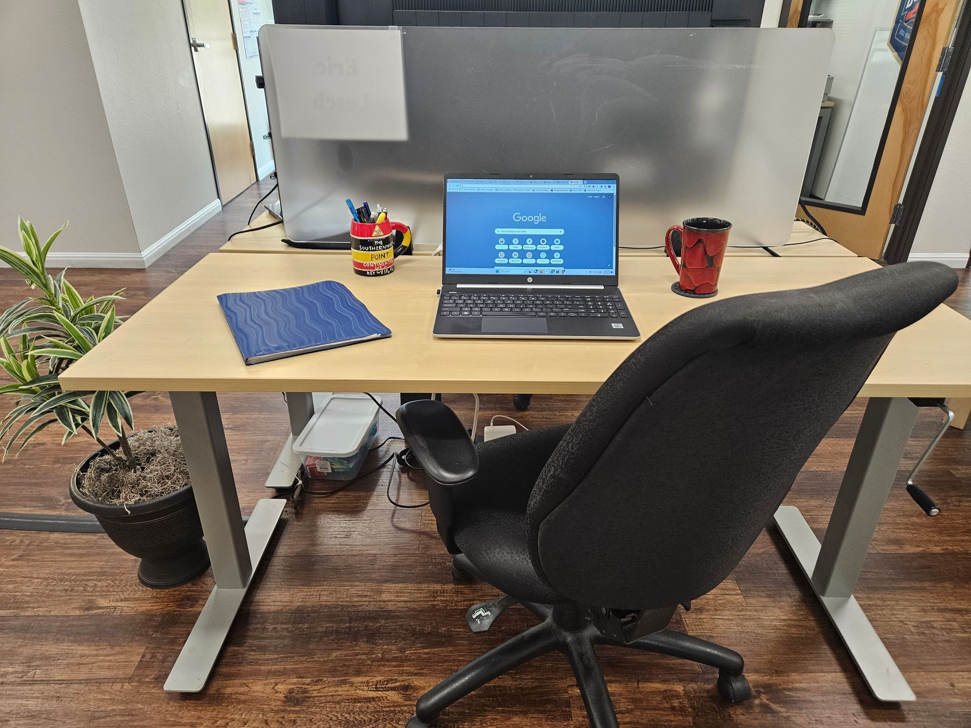 A laptop computer is sitting on a wooden desk next to a chair.
