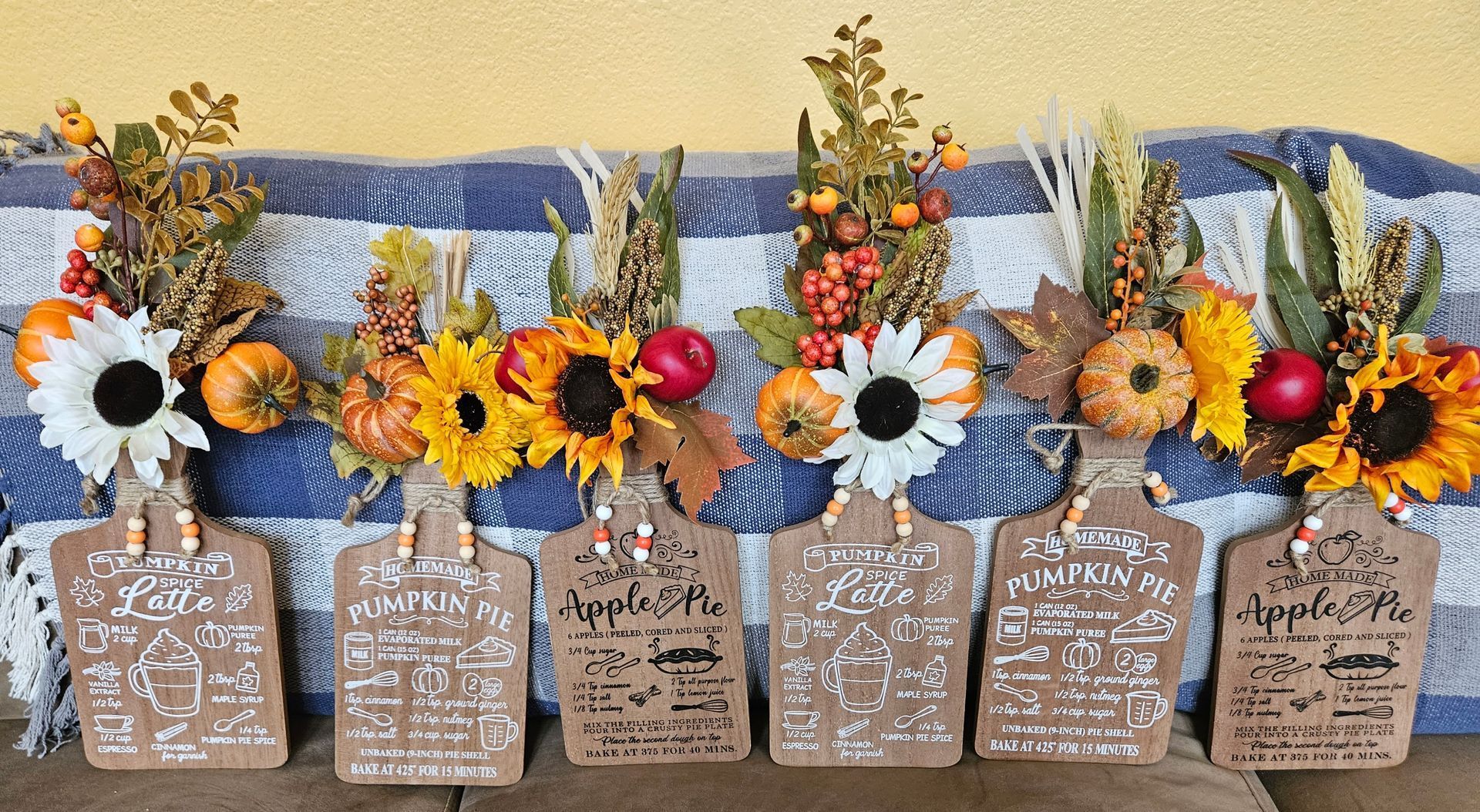 A row of vases filled with flowers and leaves on a table.