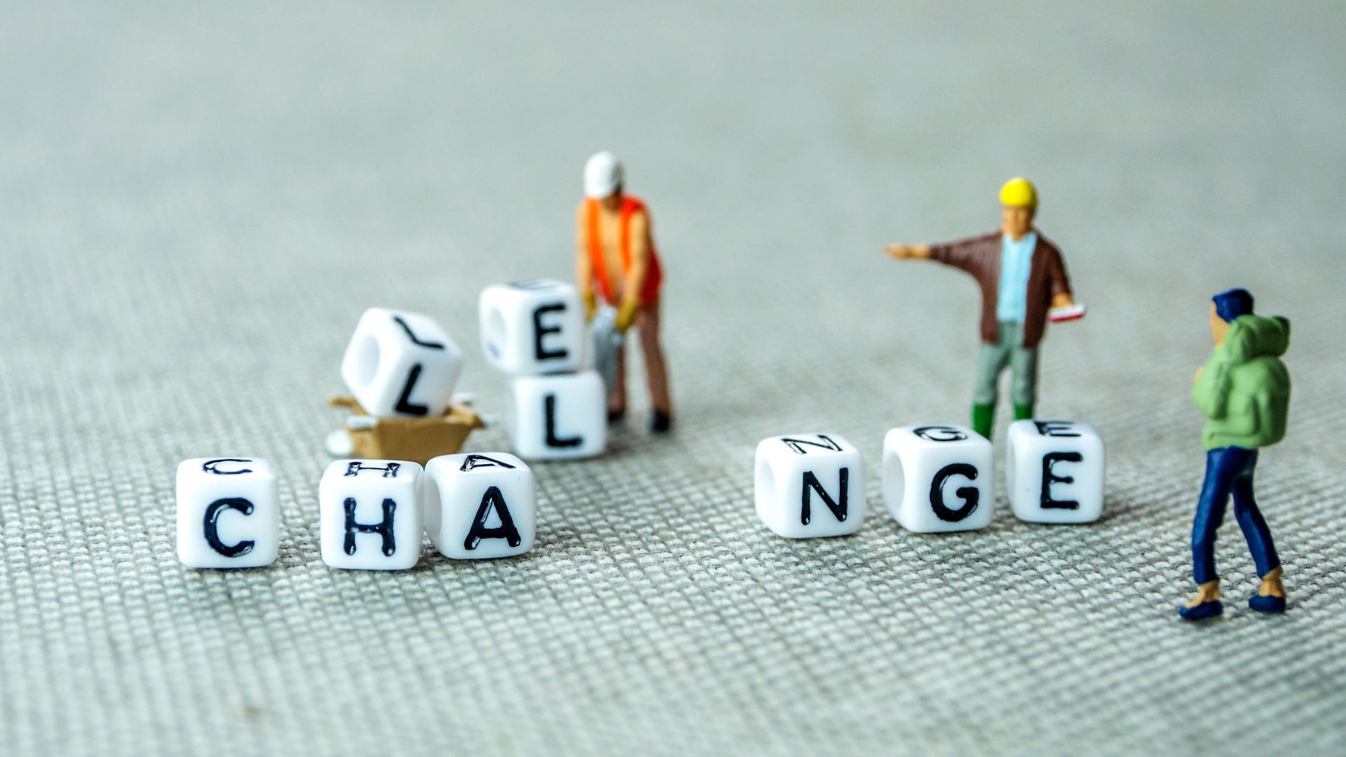 A group of miniature people are standing around dice that spell out the word change.