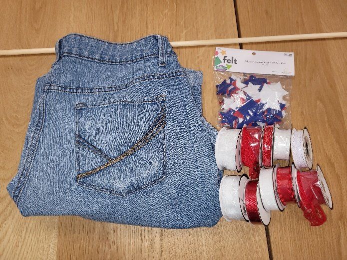 A pair of jeans is sitting on a wooden table next to ribbons and confetti
