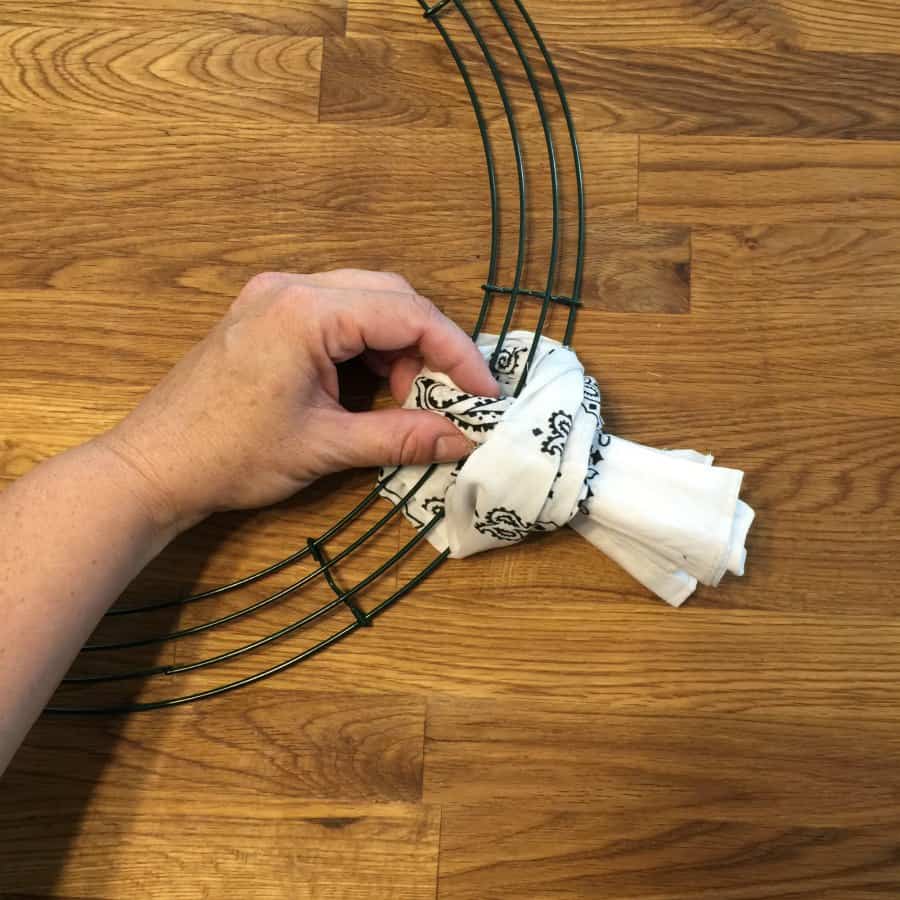 A person is tying a bandana around a wire wreath frame