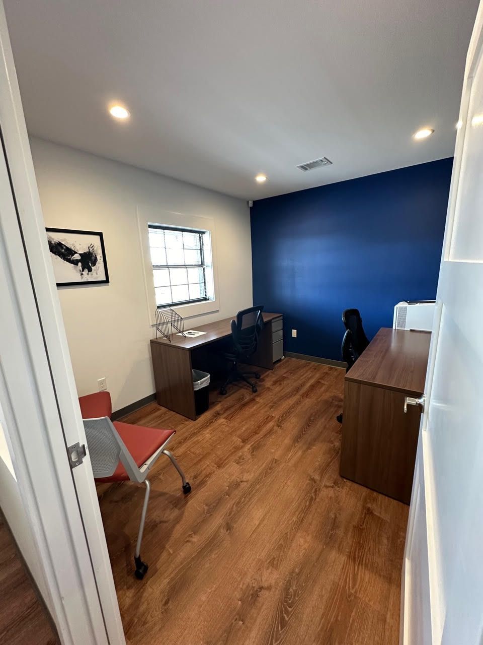 A room with a desk , chair , and window.
