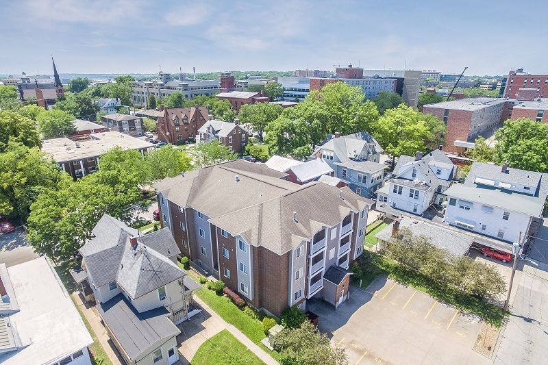 Aerial view of a brick apartment building among homes and trees in a residential neighborhood