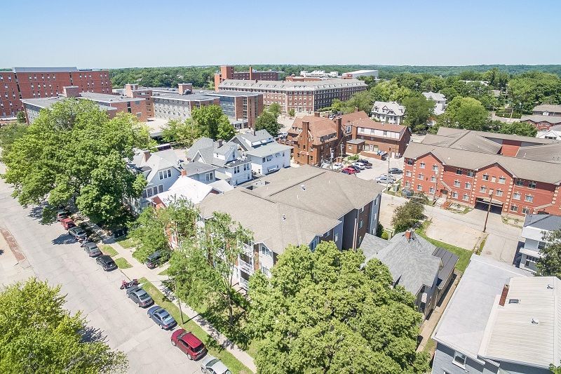 Aerial view of a leafy neighborhood with houses, trees, and parked cars on a sunny day
