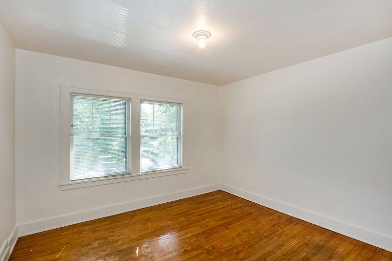 Empty white room with hardwood floors and a window with blinds