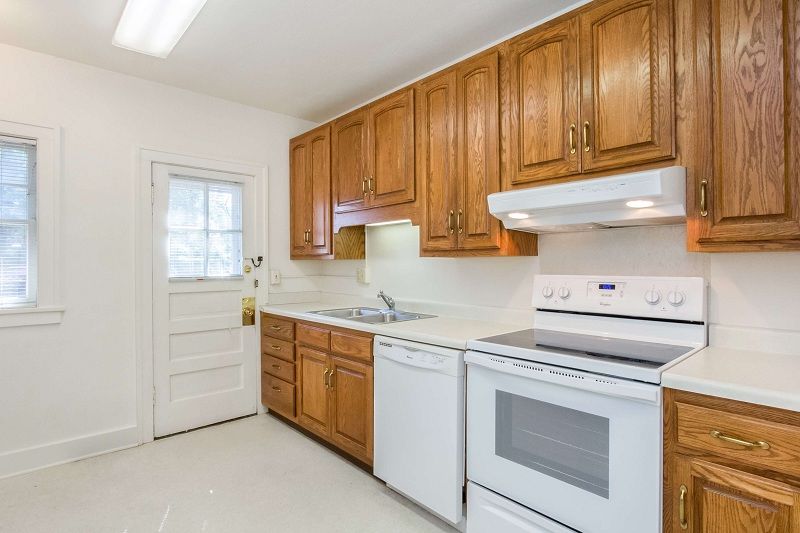 Bright kitchen with wooden cabinets, white appliances, and a back door with windows