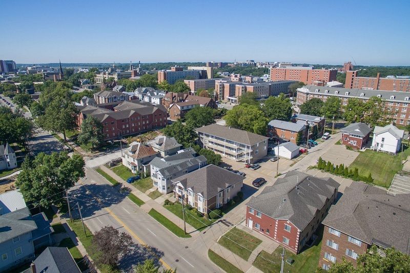 Aerial view of a suburban neighborhood with houses, trees, and low-rise buildings on a sunny day