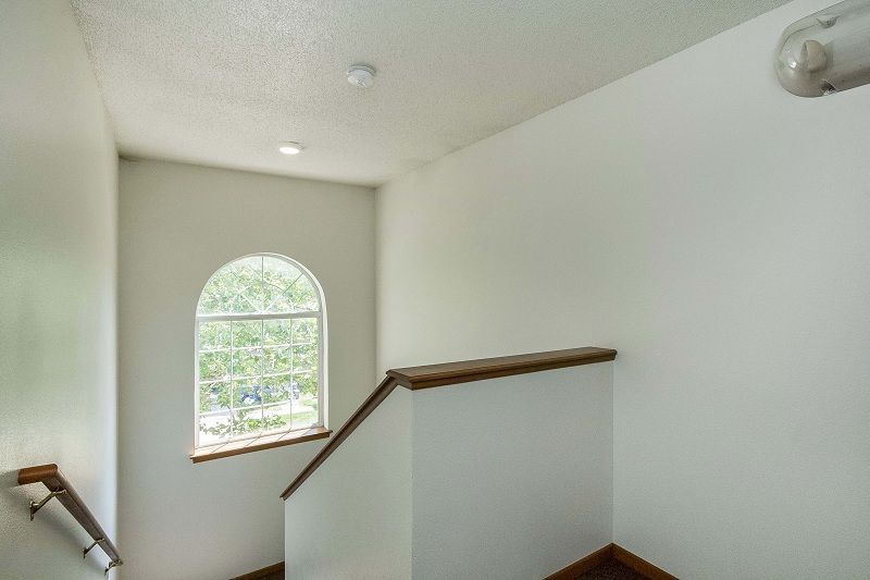 Empty white staircase landing with arched window and wooden handrails