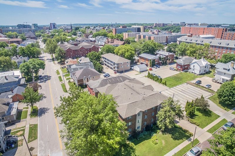 Aerial view of a suburban neighborhood with houses, trees, streets, and a distant city skyline