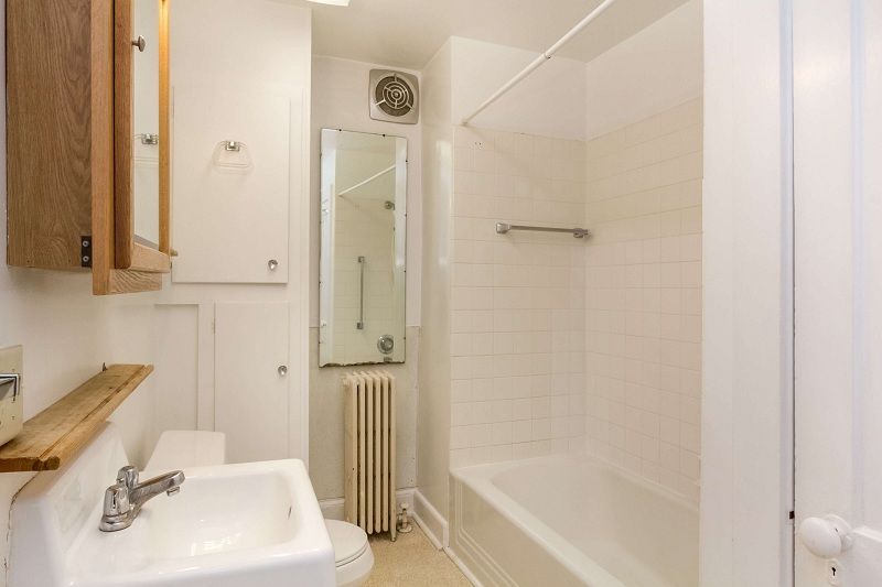 Small white bathroom with sink, mirror, radiator, and bathtub/shower combo.