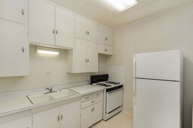 Bright white kitchen with cabinets, sink, stove, and refrigerator.