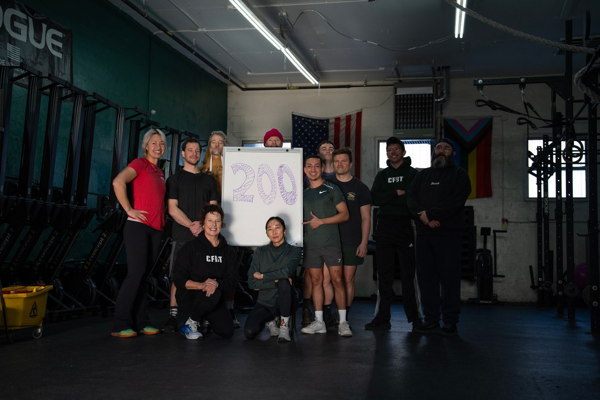 Group of people in a gym holding a sign, posing together under dim lighting.