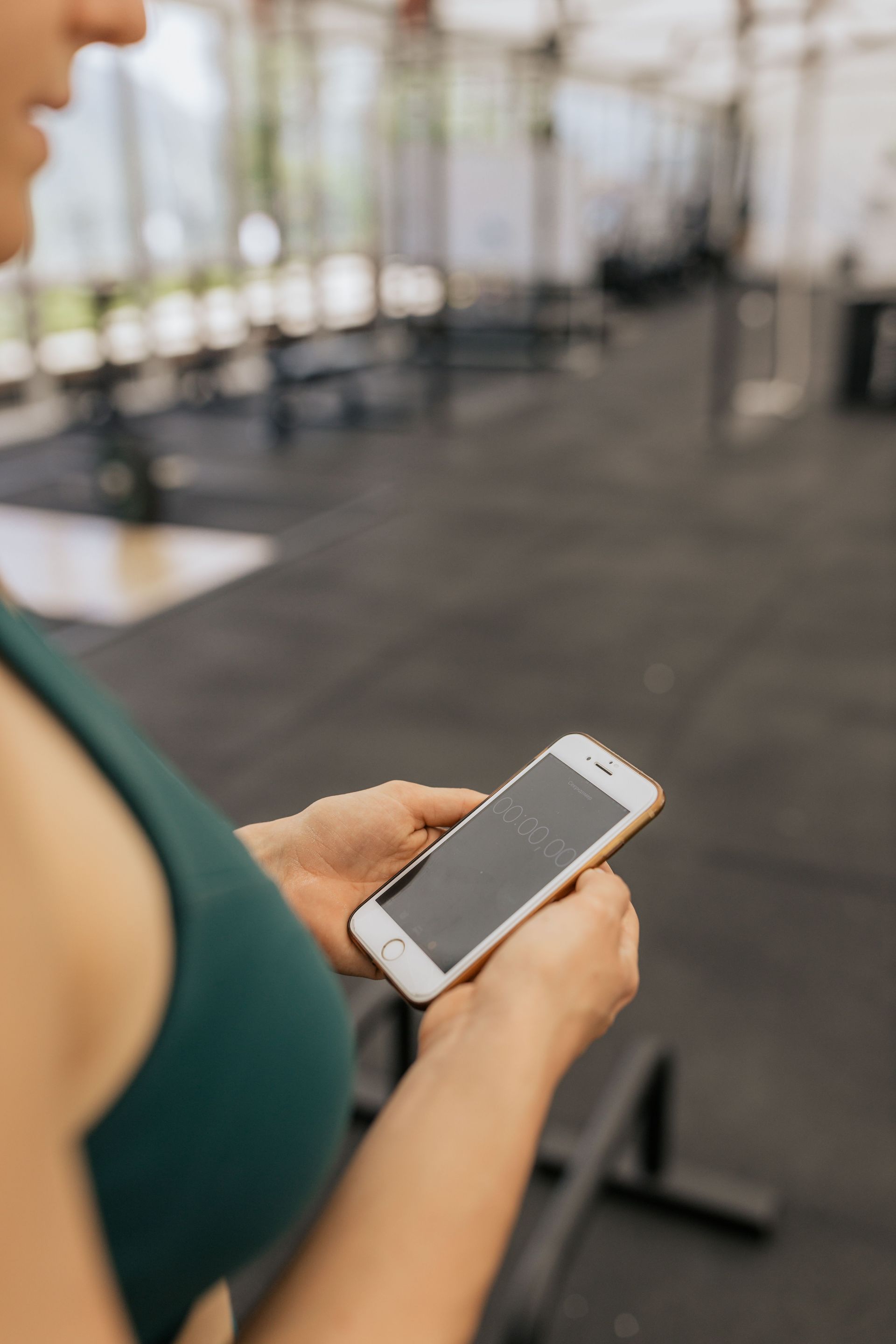 Person holding a smartphone in a blurred gym or fitness studio setting